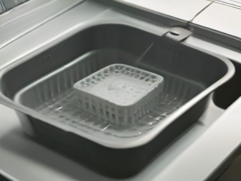 Soaking an air fryer basket to loosen stubborn baked-on grease