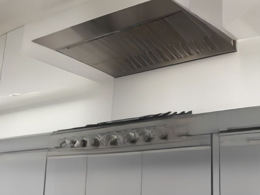 A grease free range hood shining under warm overhead lights.