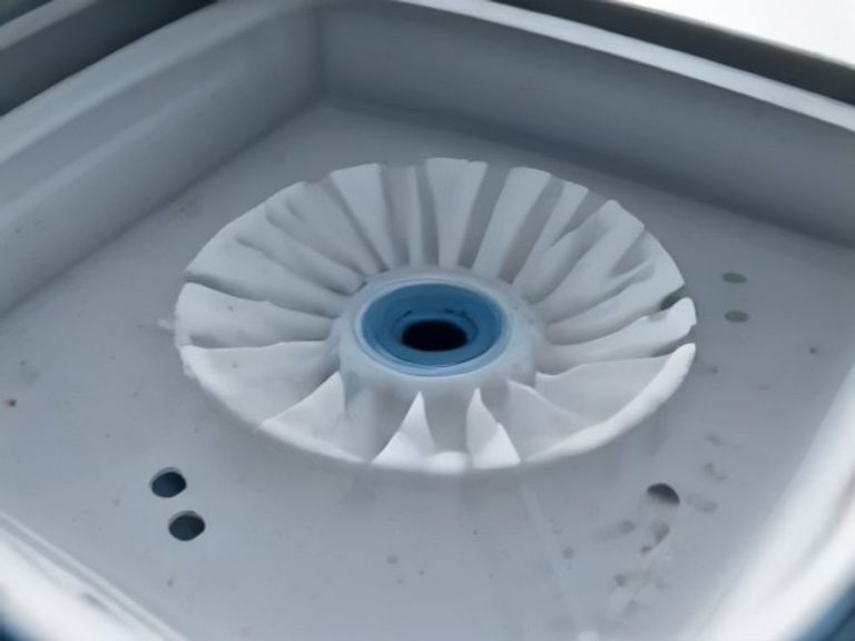 A small brush cleaning a clogged dishwasher spray arm.