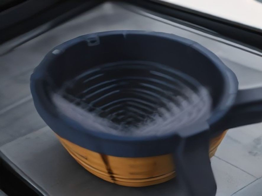 A close up of a small microfiber duster cleaning an air fryer heating element.