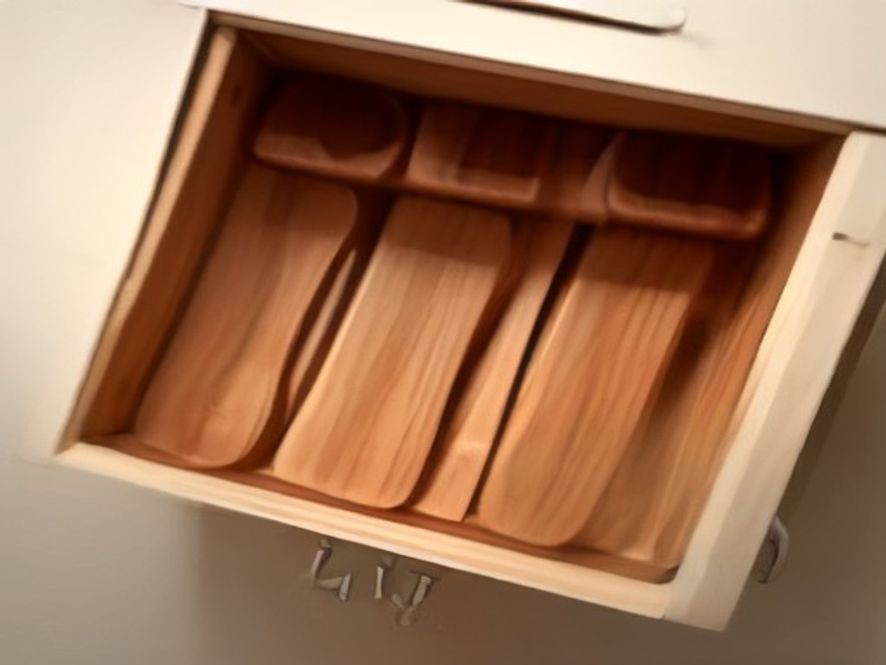 Pegged wooden insert holding nested stainless steel measuring cups and spoons