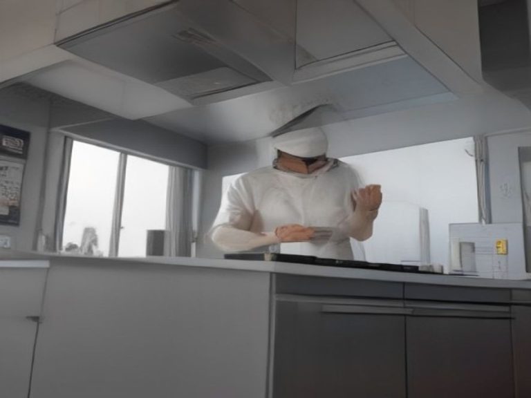 A metal mesh range hood filter resting on a counter during cleaning.